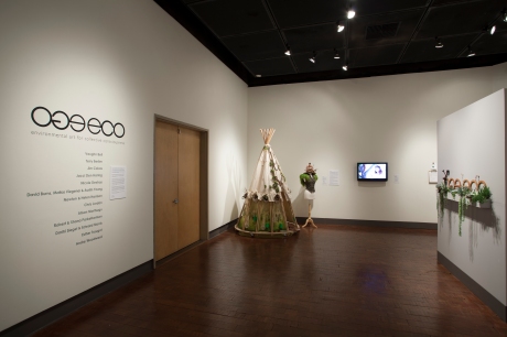 Gallery entrance view with title wall, Traveling SeedBomb dress and dress form with vest and hat and Urban Forgers video beside it. Photo: M.O.Quinn